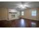 Spacious living room featuring a brick fireplace, hardwood floors, and natural light from two windows at 18015 Palm St, Umatilla, FL 32784