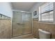Bathroom featuring tiled shower with glass door, tiled walls and a window for natural light at 2003 Cordero Ct, The Villages, FL 32159