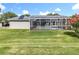 Grey house featuring a screened in pool, set on a lush green lawn at 2024 Meadowside Dr, Eustis, FL 32726
