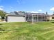 View of the back of a house with a screened in pool, grey siding and a grassy lawn at 2024 Meadowside Dr, Eustis, FL 32726