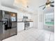Bright kitchen with white cabinets, stainless steel appliances, and tile flooring, illuminated by natural light at 2024 Meadowside Dr, Eustis, FL 32726