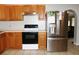 Functional kitchen with tile flooring, wood cabinets, stainless steel refrigerator, and modern black range at 23515 Poinsettia Ave, Fruitland Park, FL 34731