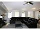 Spacious living room featuring a comfortable black sectional sofa, ceiling fan, and ample natural light at 23515 Poinsettia Ave, Fruitland Park, FL 34731