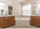 Spacious bathroom with a soaking tub, dual vanities, and a large window for natural light at 245 Blue Cypress Dr, Groveland, FL 34736