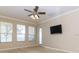 Bright bedroom with carpeted floors, large windows, ceiling fan, and mounted flatscreen TV at 245 Blue Cypress Dr, Groveland, FL 34736