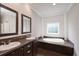 Bright bathroom featuring double sinks, a soaking tub, and neutral walls, creating a clean and relaxing space at 25156 Buttonwood Dr # 126, Astatula, FL 34705
