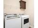 Bright laundry room with white washer and dryer, cabinet, and shelving for easy organization at 25156 Buttonwood Dr # 126, Astatula, FL 34705