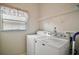Bright laundry room features a modern white Maytag washer and dryer, and convenient overhead shelving at 25406 Crestwater Dr, Leesburg, FL 34748