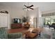 Comfortable living room with wood floors, ceiling fan, cozy seating, and access to lanai at 25406 Crestwater Dr, Leesburg, FL 34748