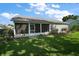 View of the back of the house featuring a screened lanai and green grass at 25406 Crestwater Dr, Leesburg, FL 34748