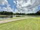 Scenic golf course view with a tranquil pond, lush greenery, and clear blue skies with fluffy white clouds at 26612 Bella Vista Dr, Howey In The Hills, FL 34737