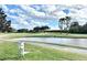 Scenic golf course view with a pond, trees and blue sky with clouds in the background at 26612 Bella Vista Dr, Howey In The Hills, FL 34737