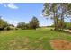 Expansive backyard view showcasing lush green grass, trees, and community golf course in the distance at 2712 Plainridge Loop, The Villages, FL 32162