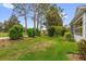 Manicured backyard with lush green grass, mature trees, and access to the community golf course at 2712 Plainridge Loop, The Villages, FL 32162