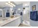 Bright bathroom featuring double sinks, vanity, glass-enclosed shower with neutral tile, and towel hangers at 2712 Plainridge Loop, The Villages, FL 32162