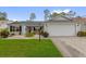 Inviting single-story home with a well-maintained lawn, a two-car garage, and colorful plants at 2712 Plainridge Loop, The Villages, FL 32162