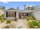 Charming home with a bright red front door and attractive landscaping at 2712 Plainridge Loop, The Villages, FL 32162