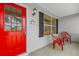 Inviting front porch with a vibrant red door and comfortable seating at 2712 Plainridge Loop, The Villages, FL 32162