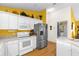 Bright kitchen with white cabinets, stainless steel appliances, and a colorful yellow accent wall at 2712 Plainridge Loop, The Villages, FL 32162