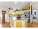 Bright kitchen with white cabinets, stainless steel appliances, and a colorful yellow accent wall at 2712 Plainridge Loop, The Villages, FL 32162
