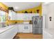 Bright kitchen with white cabinets, stainless steel appliances, and a colorful yellow accent wall at 2712 Plainridge Loop, The Villages, FL 32162