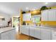 Bright kitchen with white cabinets, and a colorful yellow accent wall next to a large window at 2712 Plainridge Loop, The Villages, FL 32162