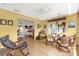Open concept living room with wood floors, yellow walls, rocking chairs, and views of the dining room at 2712 Plainridge Loop, The Villages, FL 32162