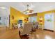 Cozy living room featuring a fan, comfortable seating, and a bright yellow accent wall at 2712 Plainridge Loop, The Villages, FL 32162