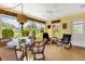 Bright sunroom with a glass-top table, rocking chairs, wood floors, and large windows overlooking the landscaped yard at 2712 Plainridge Loop, The Villages, FL 32162
