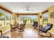 Sunroom with views of the garden, wood floors, ceiling fan, table and chairs, rocking chair, and floral valances at 2712 Plainridge Loop, The Villages, FL 32162