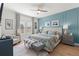 Beautiful bedroom with a ceiling fan, wood floors, stylish blue accent wall and an upholstered bed and bench at 2928 Marlberry Ln, Clermont, FL 34714
