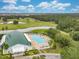 An aerial view of a pool, clubhouse, golf course, and wooded areas in a great community at 33417 Pennbrooke Pkwy, Leesburg, FL 34748