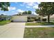 Charming single-story home with an attached two-car garage, lush landscaping, and a well-manicured lawn at 3677 Park Green Ct, Tavares, FL 32778