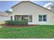 Back exterior of home featuring a screened lanai, manicured lawn, and lush landscaping at 3718 Westerham Dr, Clermont, FL 34711