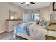 A cozy bedroom with a large window and a stylish dresser, illuminated by natural light at 4716 Heritage Trl, Leesburg, FL 34748