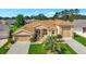 Beautifully landscaped, this tan home features an eye-catching red front door and a convenient three-car garage at 4716 Heritage Trl, Leesburg, FL 34748
