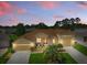 Beautifully landscaped, this tan home features an eye-catching red front door and a convenient three-car garage at 4716 Heritage Trl, Leesburg, FL 34748