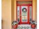 An inviting red front door is flanked by flower-filled pots and a glass-paneled sidelight at 4716 Heritage Trl, Leesburg, FL 34748