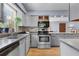Well-lit kitchen featuring gray cabinets, stainless steel oven, and hardwood floors at 5581 Sw 197Th Ter, Dunnellon, FL 34431