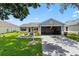 Bright home with a well-kept lawn, concrete driveway, and open two-car garage at 612 Lisbon Ln, The Villages, FL 32159