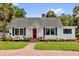 Charming one-story home featuring a brick pathway, vibrant red door, and meticulously landscaped yard at 647 E 3Rd Ave, Mount Dora, FL 32757
