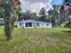 Lawn view of a one-story house with a well manicured lawn, and trees at 7378 Ne 49Th Ln, Wildwood, FL 34785