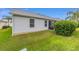Spacious backyard featuring green lawn and the white exterior of the home under a blue sky at 762 Turbeville Ter, The Villages, FL 32162
