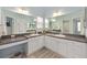 Bright bathroom featuring dual sinks, white cabinets, and a large mirror at 762 Turbeville Ter, The Villages, FL 32162