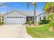 Charming single-story home featuring an attached two-car garage and lush landscaping with mature palm trees at 762 Turbeville Ter, The Villages, FL 32162