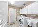 Bright laundry room featuring a washer, dryer, utility sink and storage cabinets for a tidy space at 762 Turbeville Ter, The Villages, FL 32162