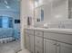 Modern bathroom with bedroom view featuring double sinks, gray cabinets, and a door to a walk-in shower at 865 Conroe St, The Villages, FL 34762