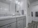 Modern bathroom featuring double sinks, gray cabinets, and a door to a walk-in shower at 865 Conroe St, The Villages, FL 34762