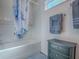 Bright bathroom features a shower, gray cabinet with modern hardware, complemented by stylish blue accents at 865 Conroe St, The Villages, FL 34762