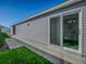 Exterior view of home with vinyl siding, green grass, a cement walkway, and sliding glass doors at 865 Conroe St, The Villages, FL 34762